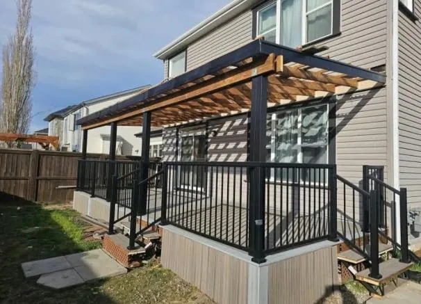 A raised composite deck with black railings and a timber pergola